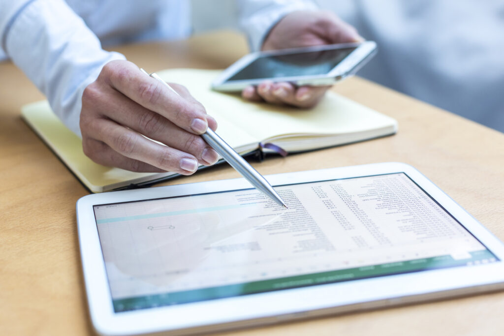 person using tablet, mobile phone, and notebook for work