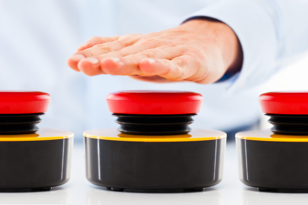 person pressing one of three red buzzers