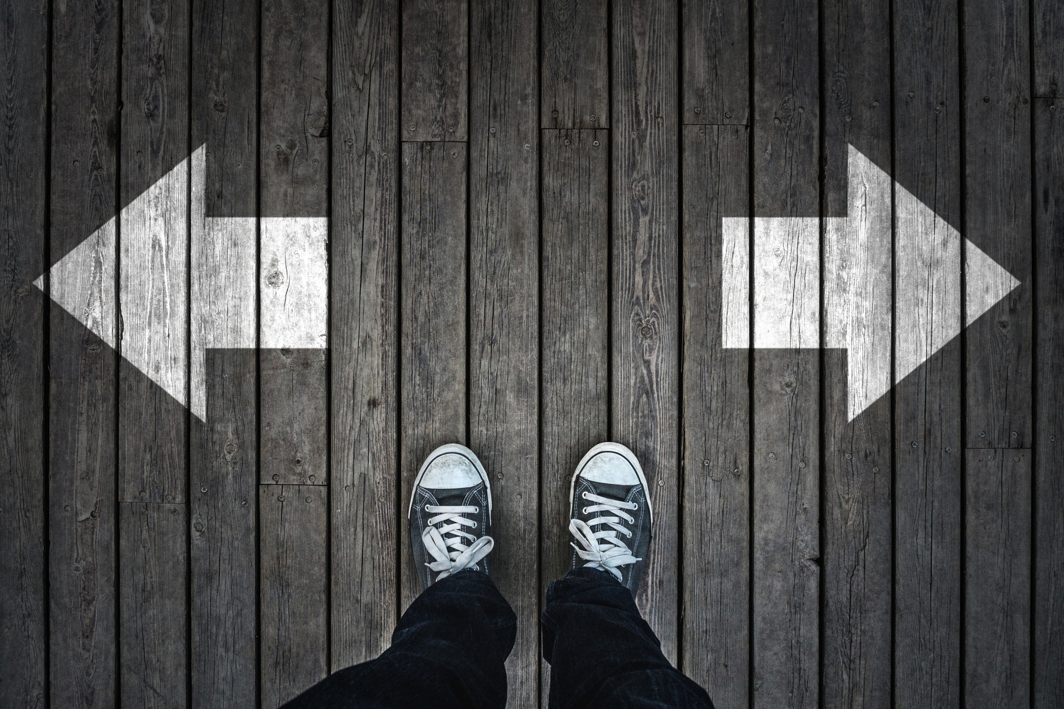 two arrows on wood with feet standing in middle