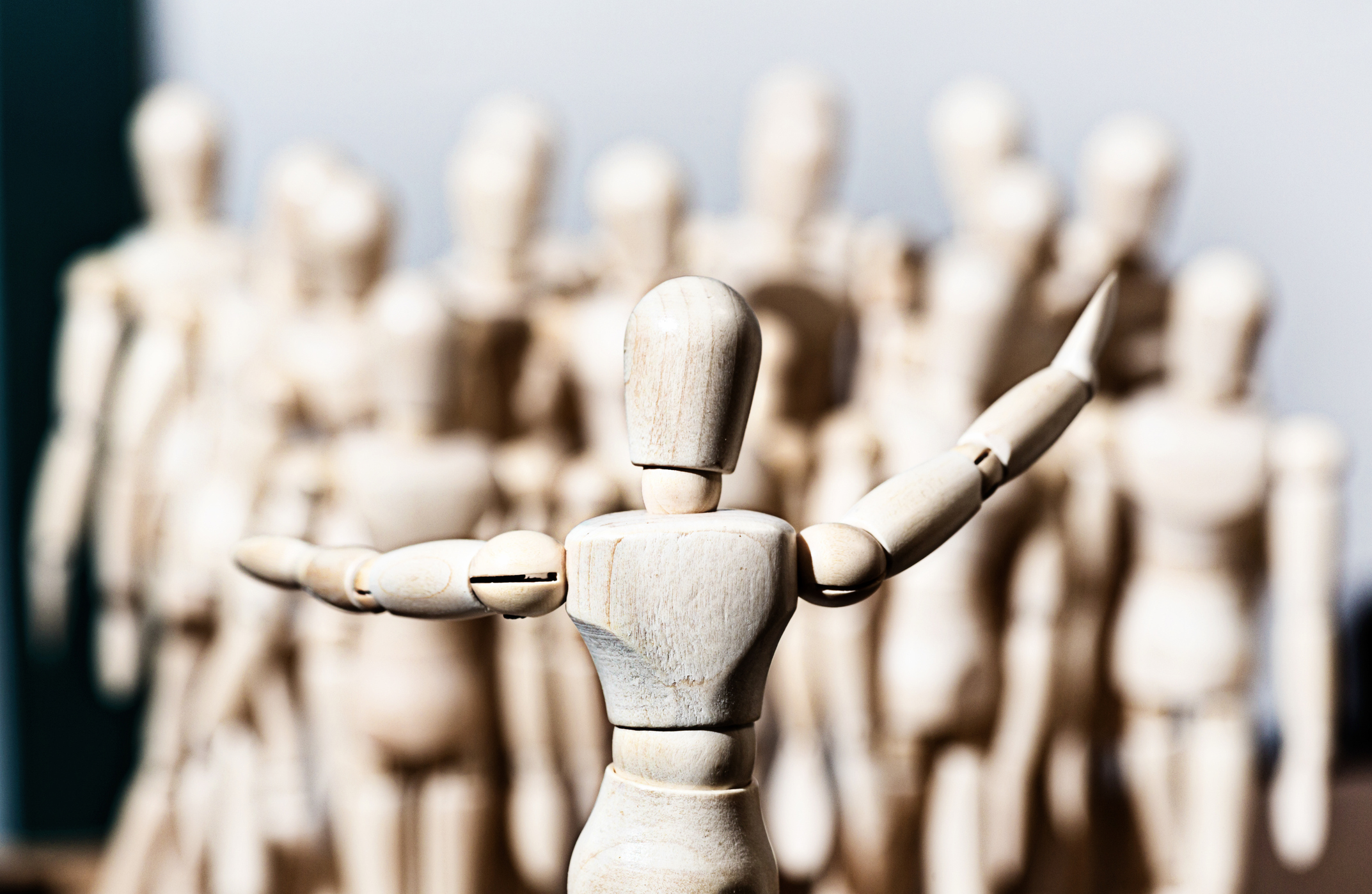 wooden figure standing in front of crowd of wooden figures