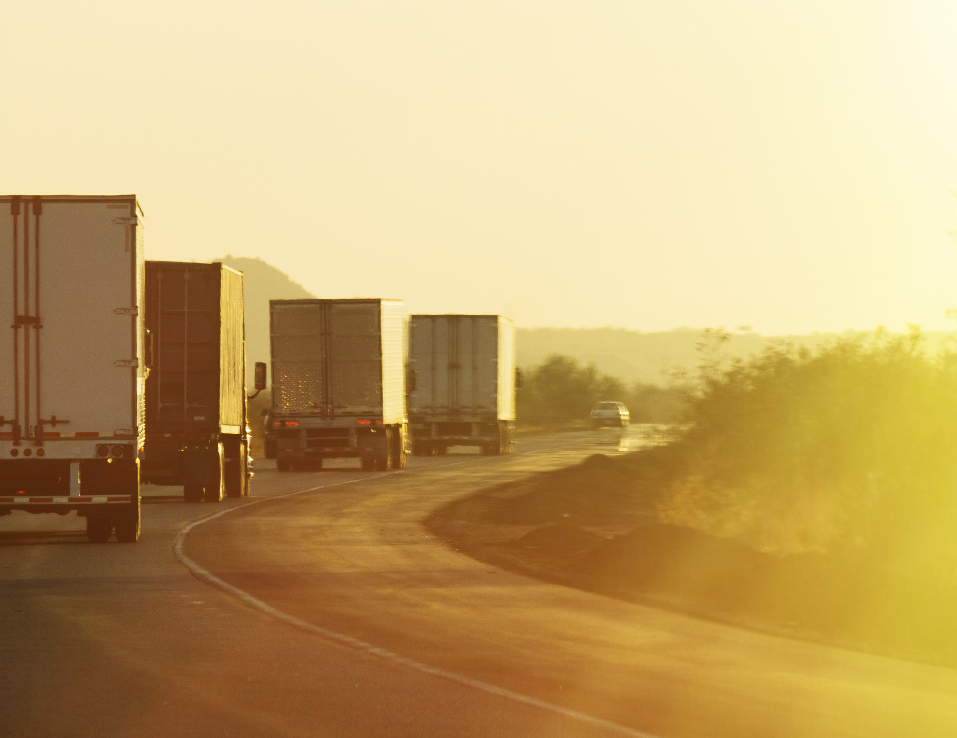 trucks convoy driving at sunrise