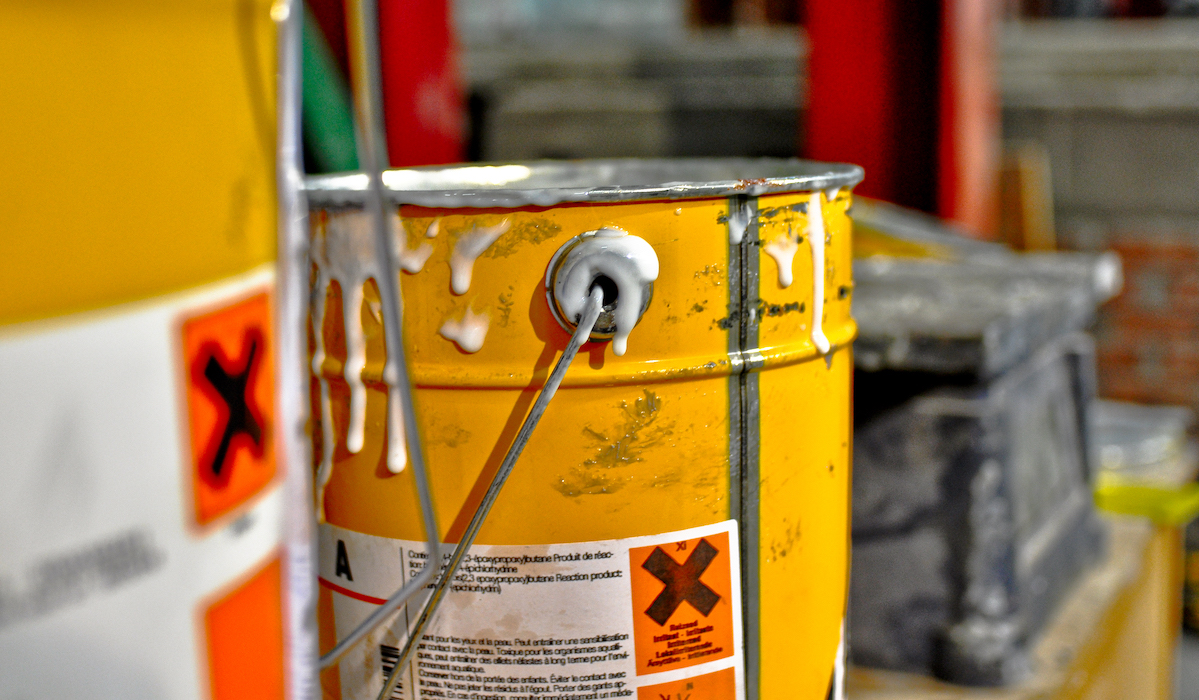 A close-up shot of a bucket dripping with toxic resin an example for businesses who need to focus on chemical spill and leak compliance training